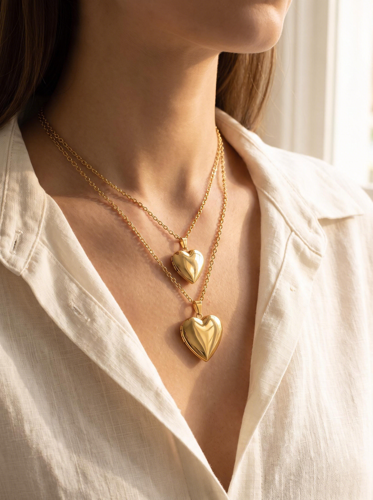 Small and large gold heart lockets worn together, true to size